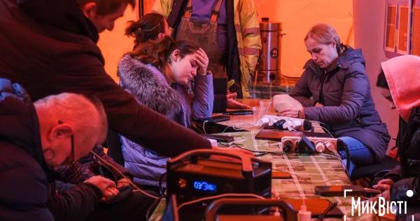 Mennesker i et opvarmet telt oplader telefoner
